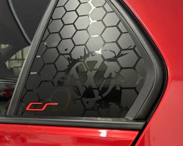 Car window with a honeycomb pattern decal and a logo on a red car. volkswagen golf Club Sport