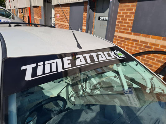 A black vinyl sticker with the text 'Time Attack' written in white, placed on the Front windscreen of a car. Sunstrip