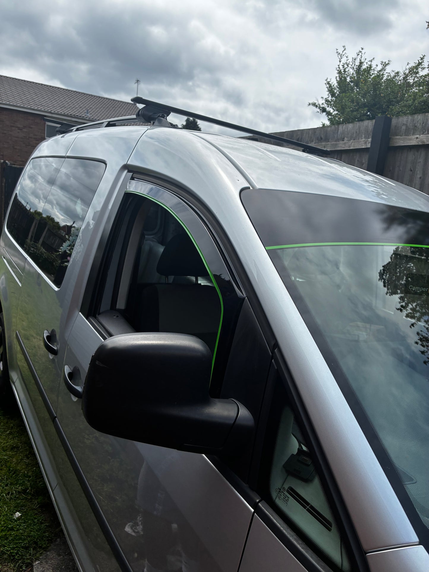 a silver van parked on a grassy area, with a cloudy sky in the background.